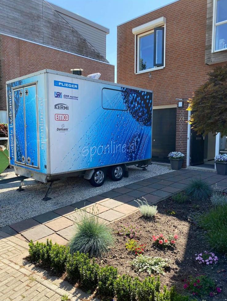 Mobiele badkamer van Badkamers Van Dijk op de oprit bij een klant