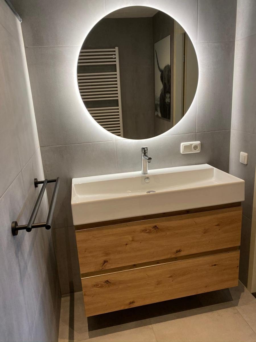 Badkamer 12: eiken meubel en ronde lichtspiegel