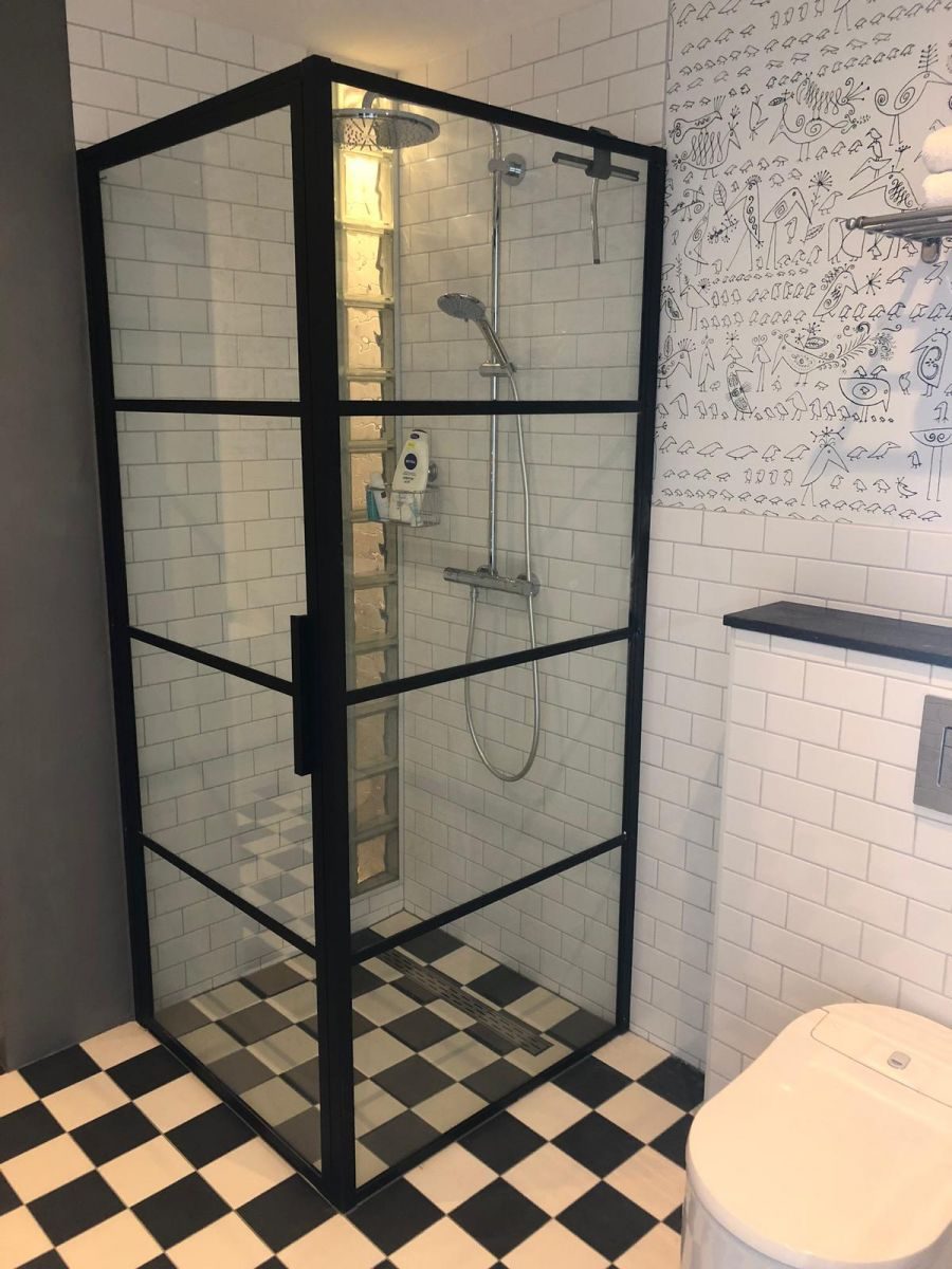 Douche met zwarte stalen glaswand en zwart-witte tegelvloer