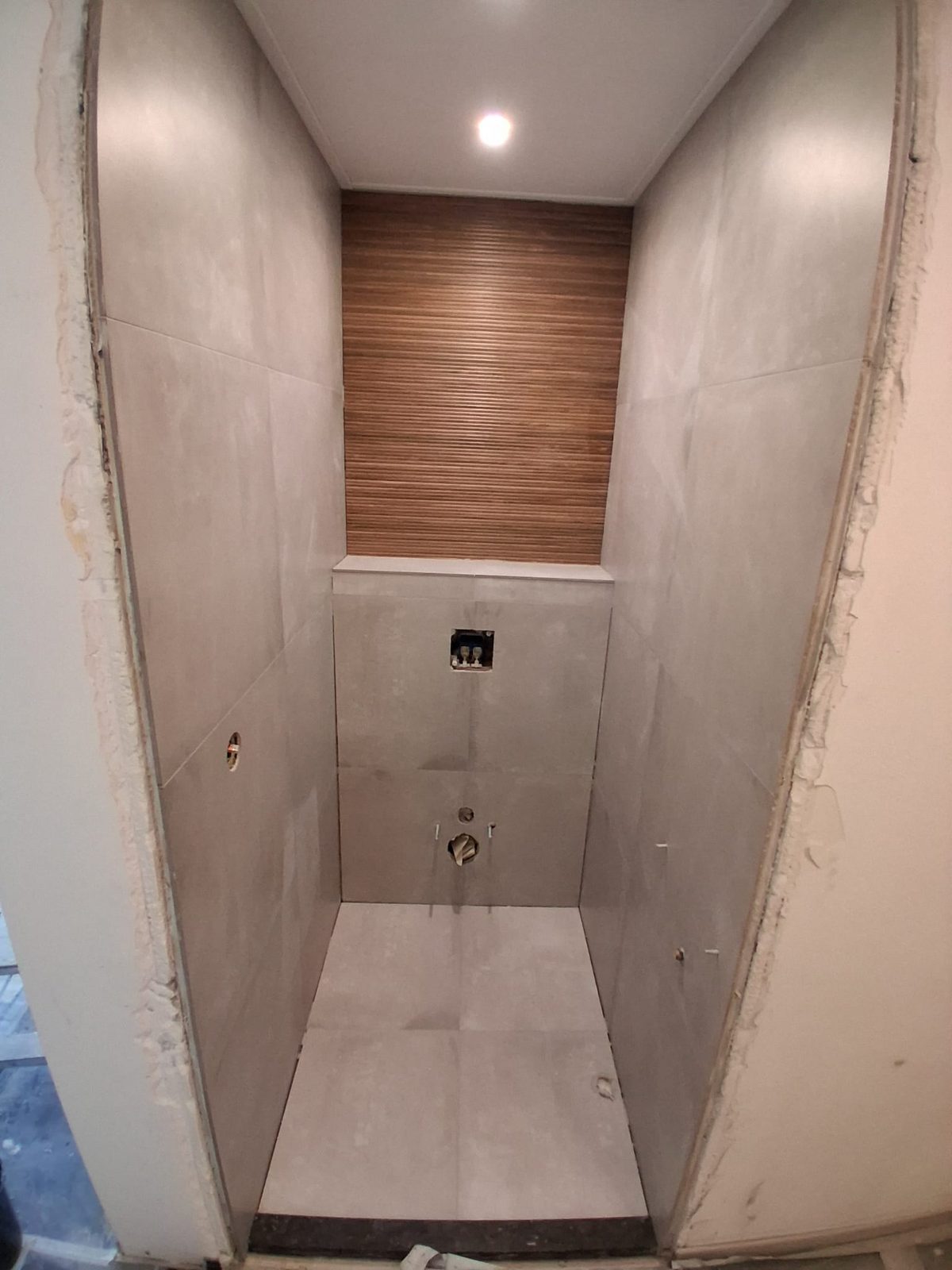 Badkamer in uitvoering: grote wandtegels met een accentwand in houtlook